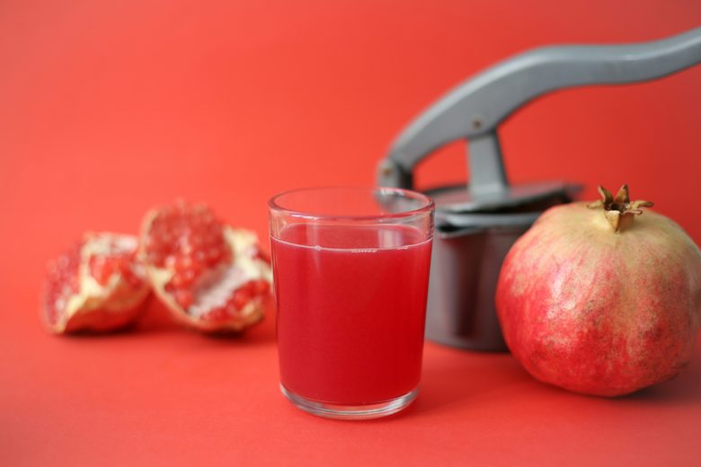 A glass of pomegranate juice beside a fresh pomegranate